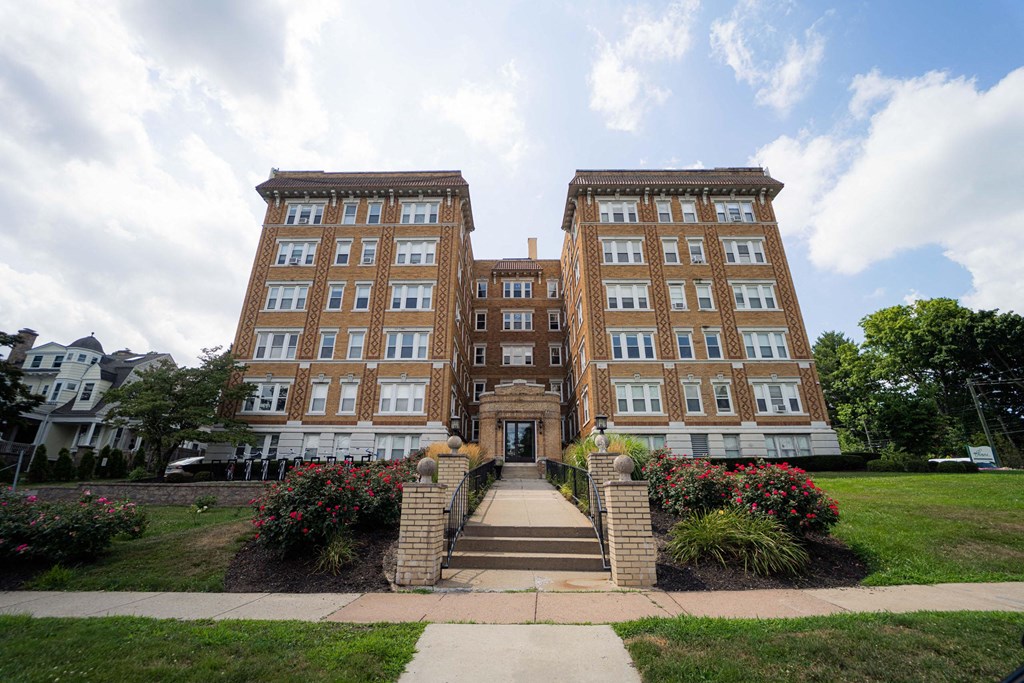 a large brick building with stairs and a garden in front of it