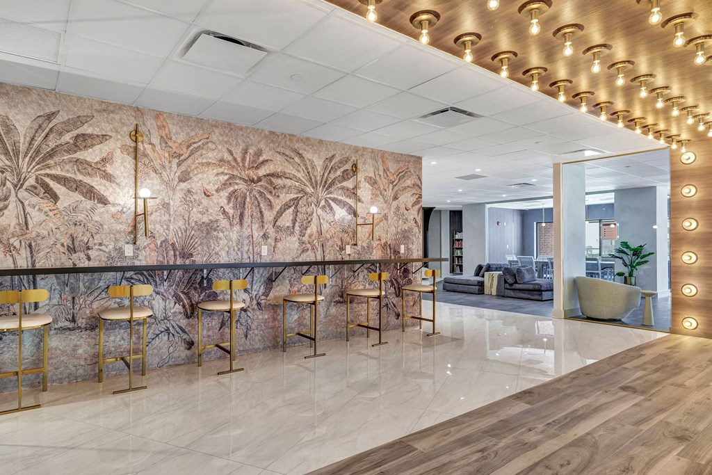 a lobby with a bar with chairs and a wall mural of palm trees