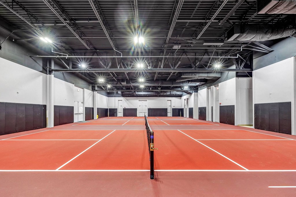 a tennis court in a building with lights on the ceiling