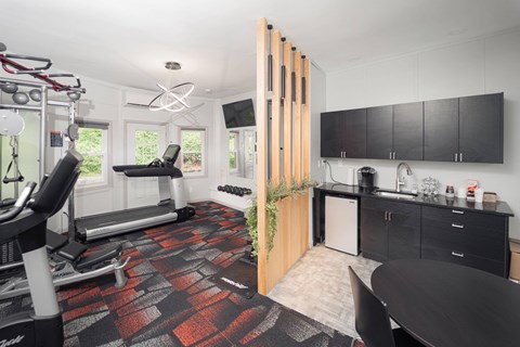 a gym with a reformer exercise machine and a kitchen with black cabinets