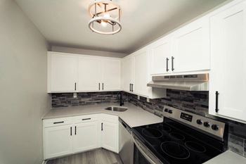a kitchen with white cabinets and a black stove at Five High, West Hartford