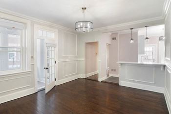 an empty living room and kitchen with white walls and wood floors at The Packard, West Hartford, 06119