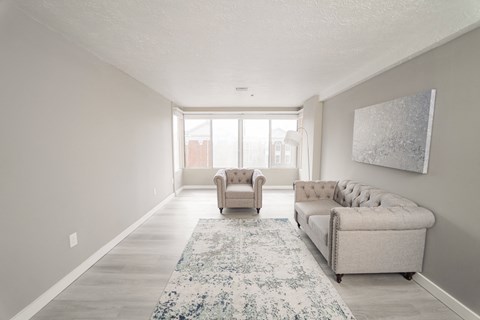 a living room with a couch and two chairs and a rug