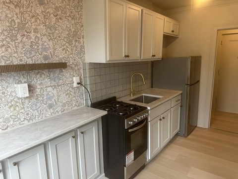 A kitchen with a black stove top oven and a refrigerator.