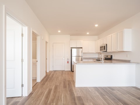A kitchen with white cabinets and a wooden floor.