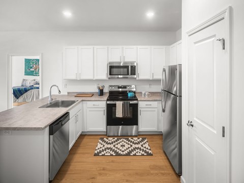 A kitchen with white cabinets and a black and white rug on the floor.