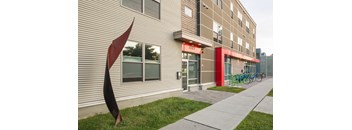 A modern building with a red awning and a sculpture in front of it.