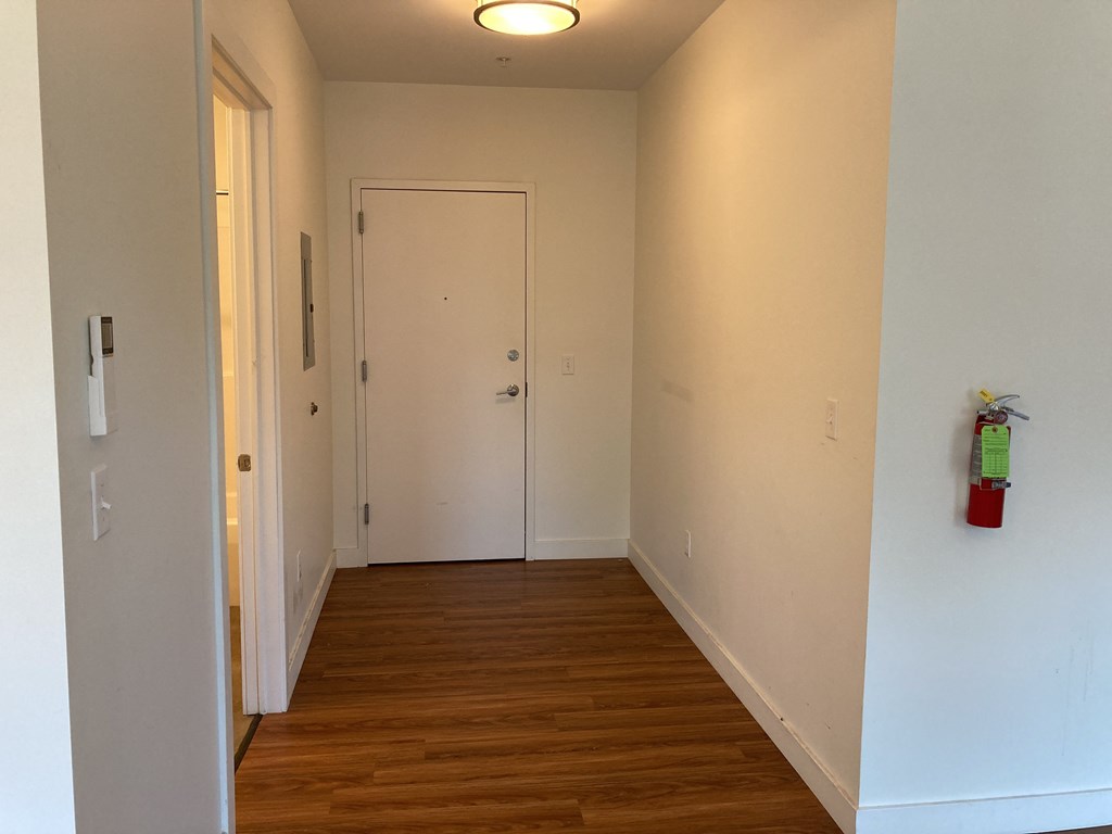 A hallway with a door and a fire extinguisher on the wall.