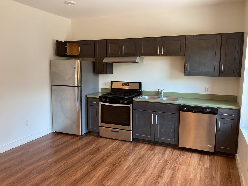 A kitchen with a refrigerator, oven, and sink.