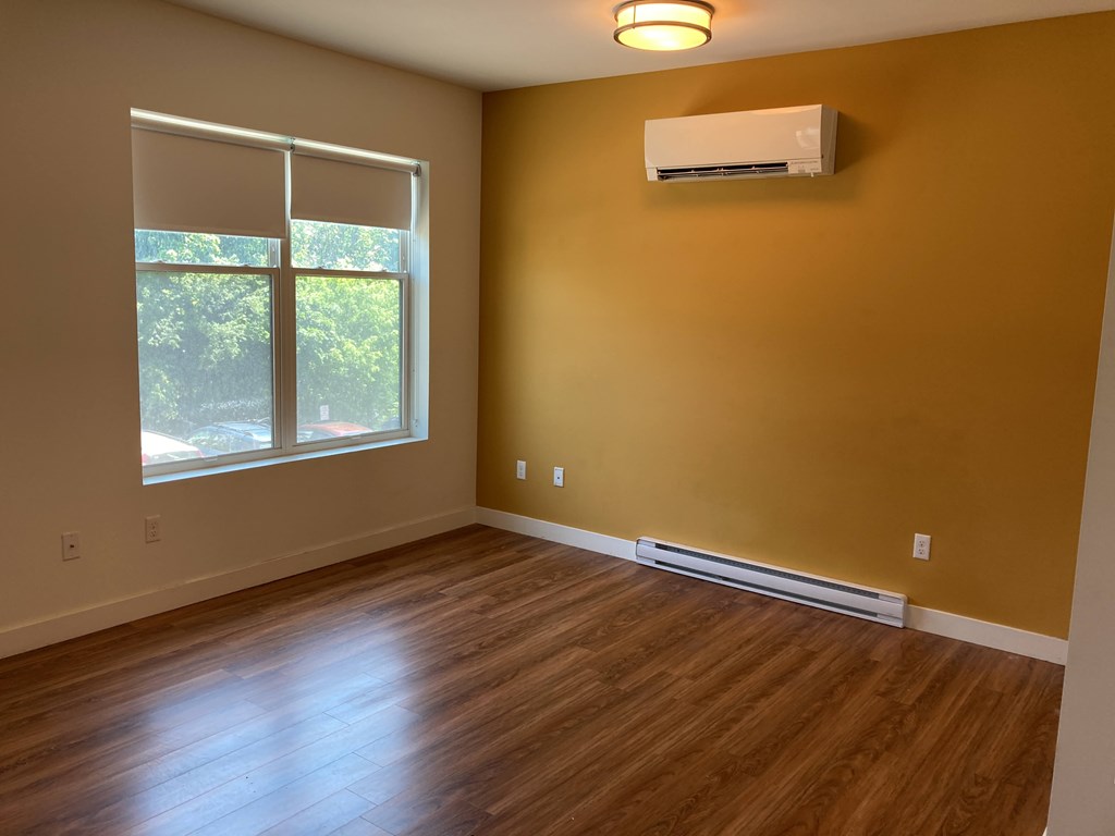 A room with a window and a wall-mounted air conditioner.
