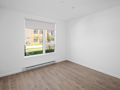A room with a window showing a view of a building and greenery outside.
