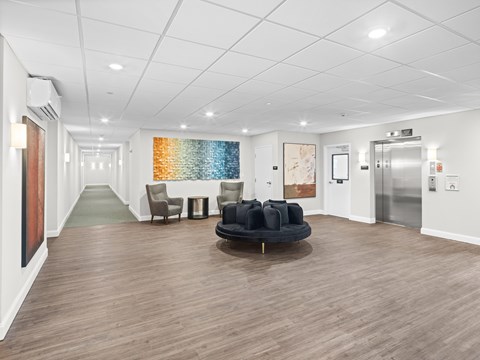 A spacious waiting room with a round black sofa and chairs.