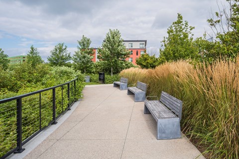 A concrete walkway with benches and a metal railing.
