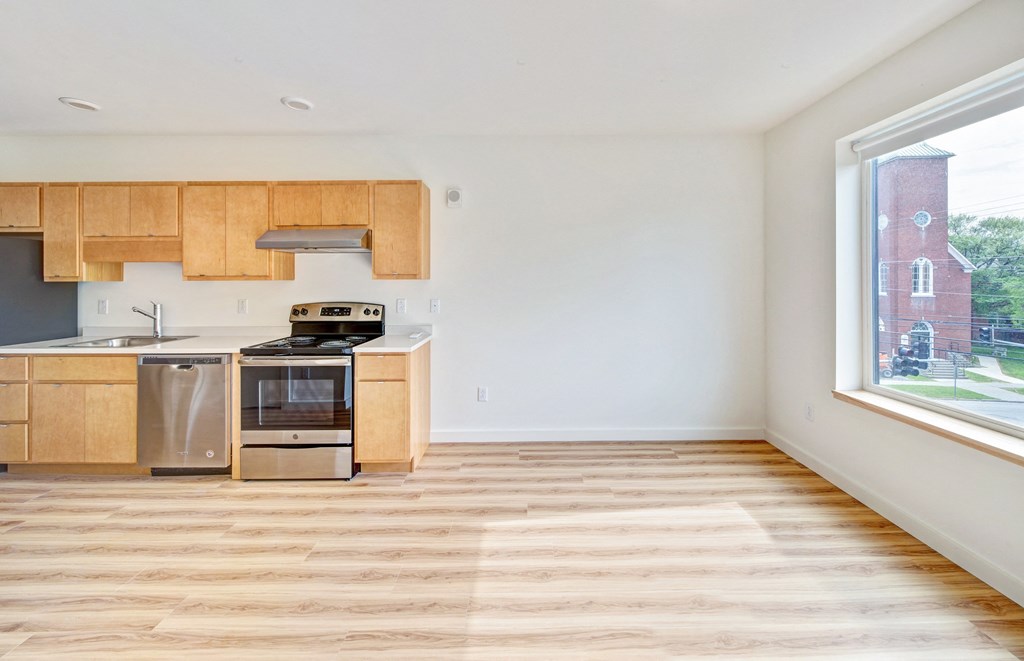 an empty kitchen with wood flooring and a large window