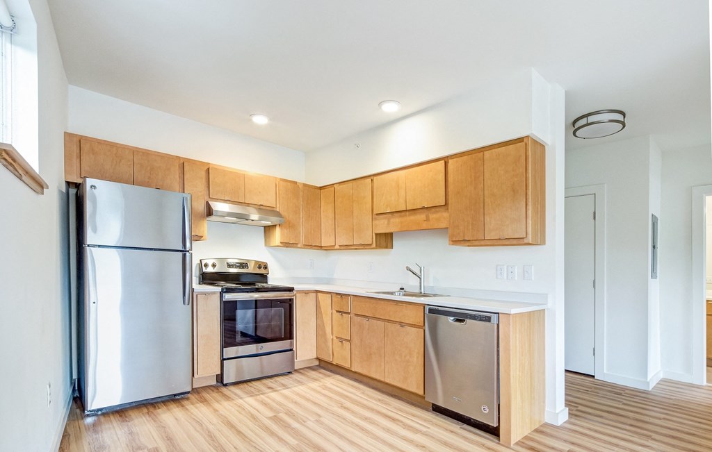 an empty kitchen with wooden cabinets and stainless steel appliances