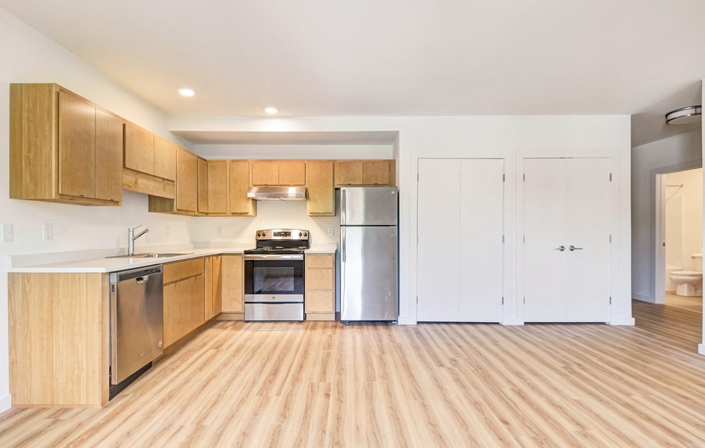 a kitchen with wood flooring and wooden cabinets and stainless steel appliances