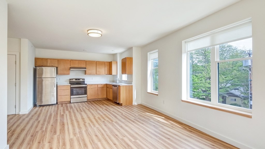 an empty kitchen with wood flooring and a large window