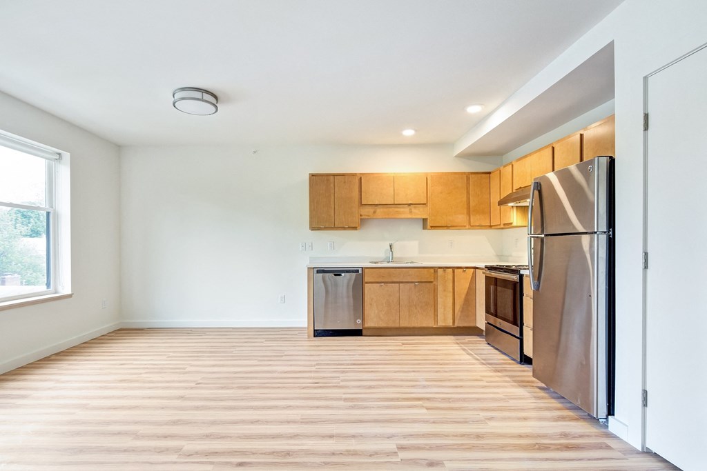 an empty kitchen with wooden floors and stainless steel appliances