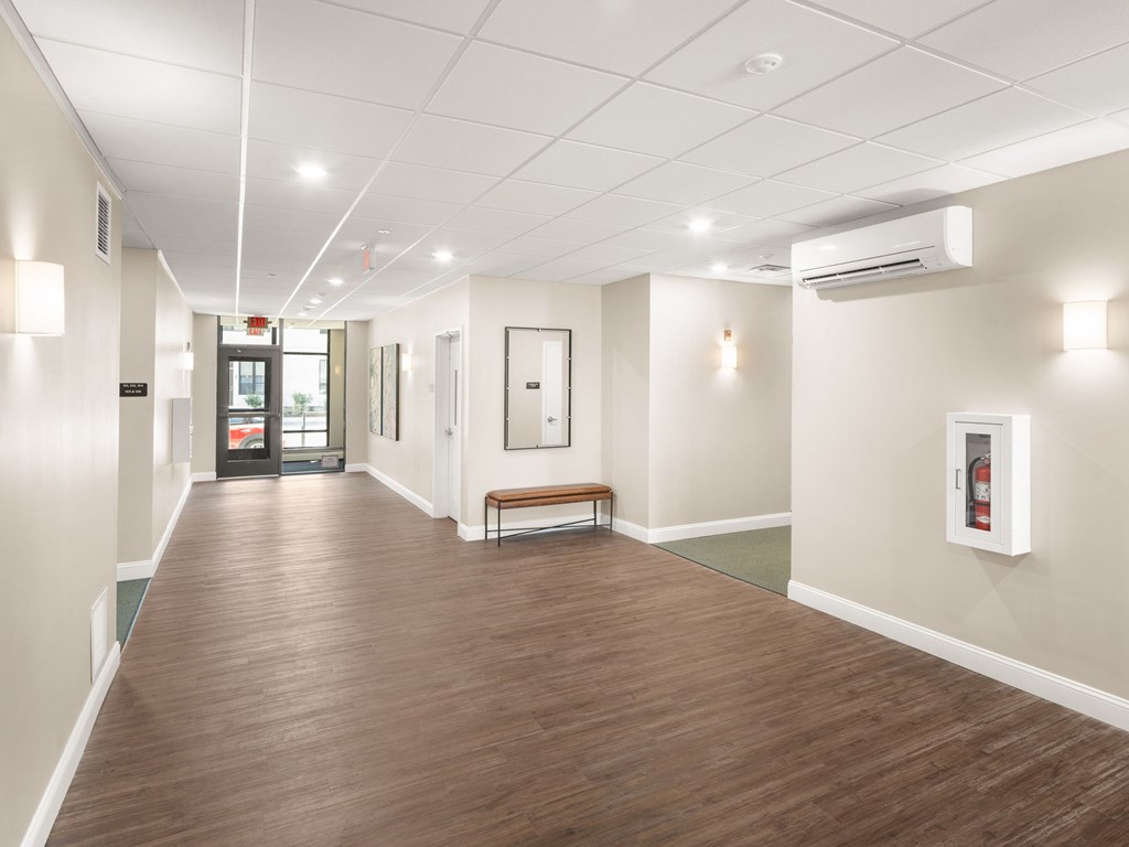 A long hallway with a bench and a fire extinguisher on the wall.