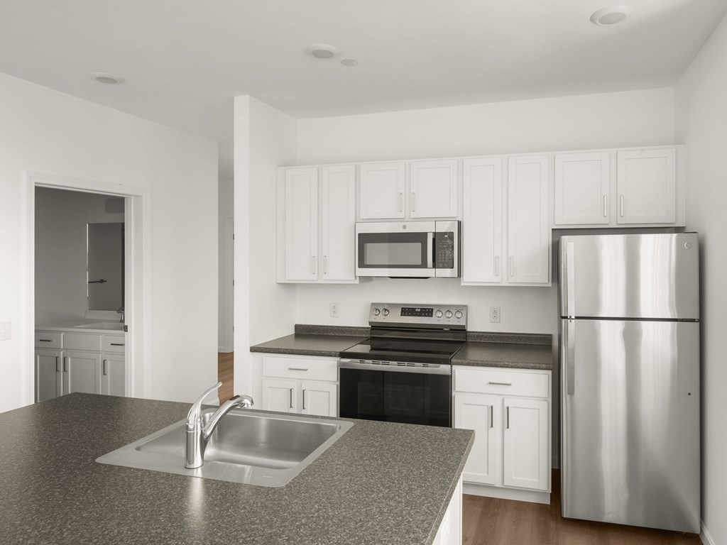 A kitchen with a stainless steel refrigerator and microwave above the stove.