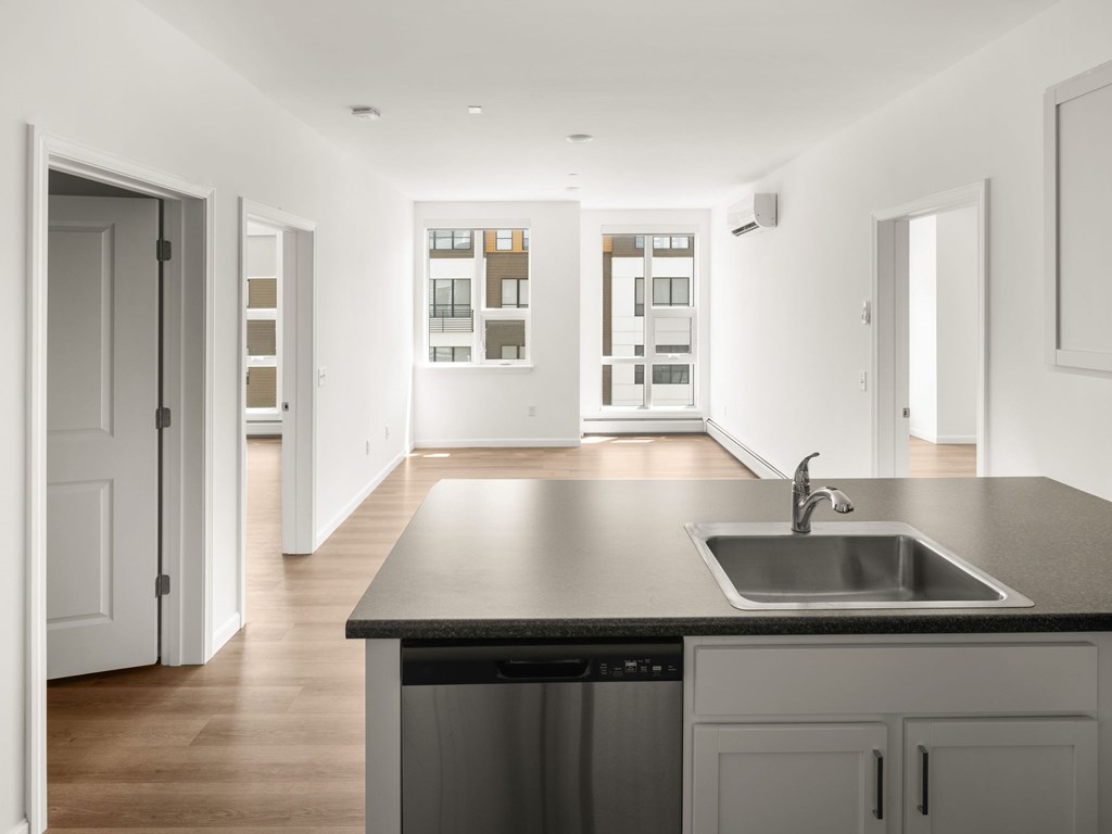 A modern kitchen with a black countertop and a stainless steel sink.