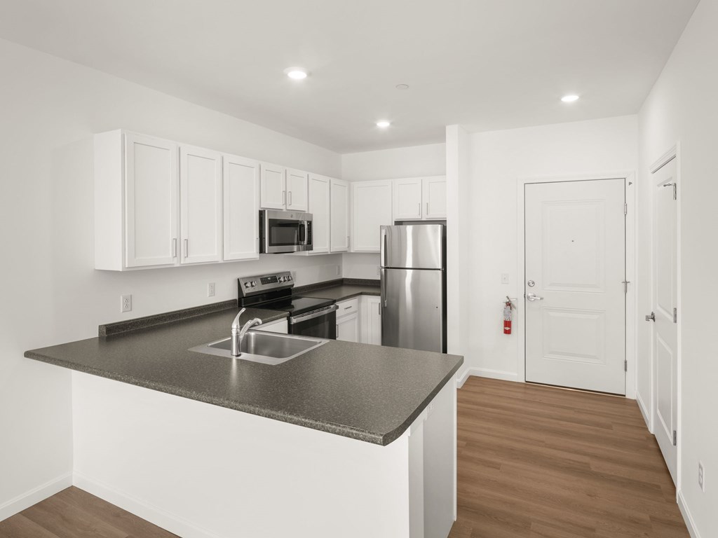 A kitchen with white cabinets and a black countertop.