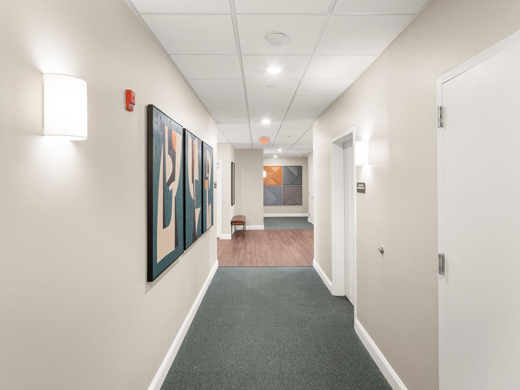 A hallway with a painting on the wall and a bench in the middle.