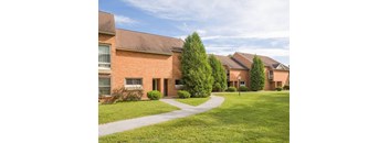 A building with a red brick exterior and a green lawn in front.