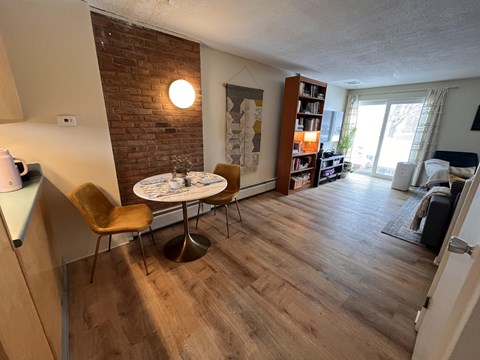 A living room with a brick wall and a round table with chairs.