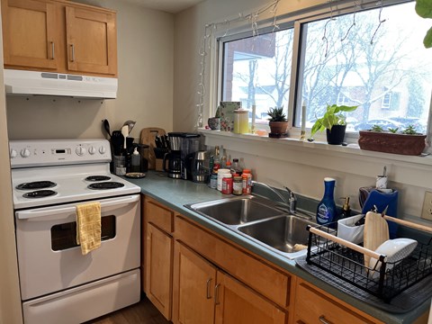 A kitchen with a white stove and wooden cabinets.