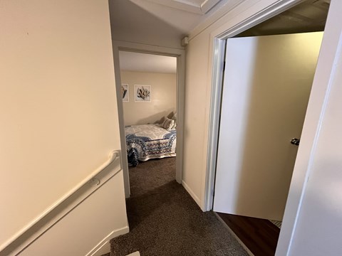 A bedroom with a bed and a carpeted floor.