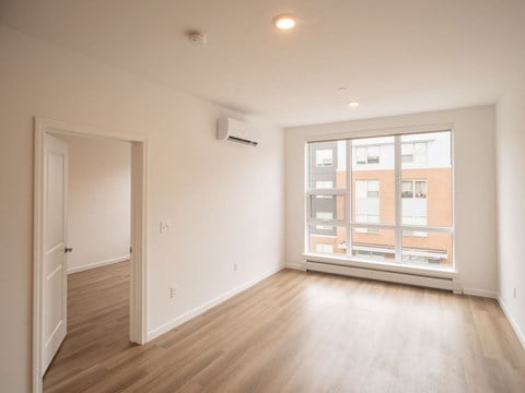 an empty living room with a large window and wooden floors