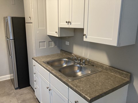 A kitchen with a sink and a refrigerator.