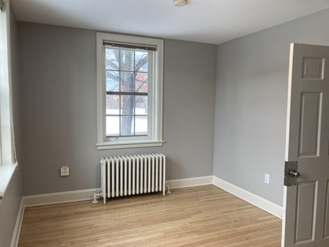 A room with a window and a radiator on the floor.