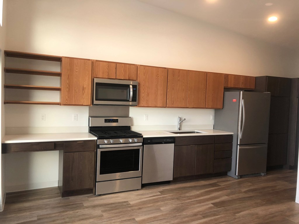 A modern kitchen with a stainless steel refrigerator, oven, and microwave.