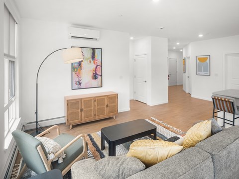 A living room with a grey couch, a wooden cabinet, and a painting on the wall.