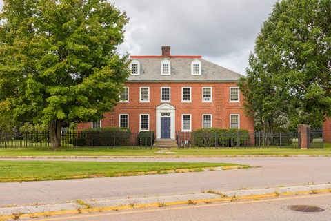 A red brick house with a black fence in front.