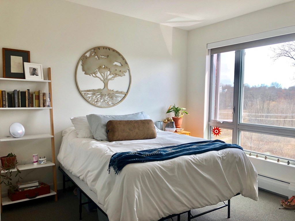 A bedroom with a large bed and a window overlooking a field.