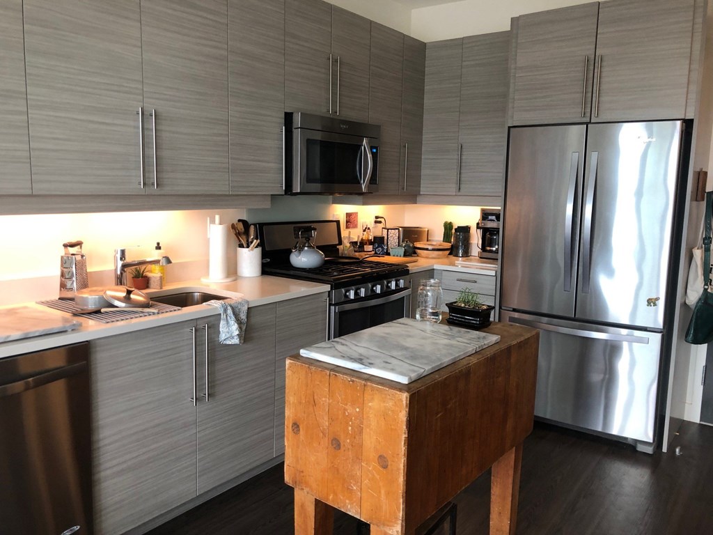 A kitchen with a wooden table and stainless steel appliances.