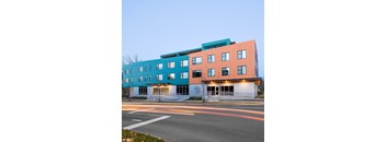 A modern multi-story building with a mix of blue and orange panels.