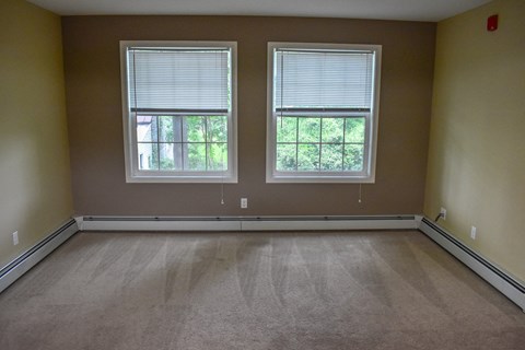an empty room with three windows and a carpeted floor