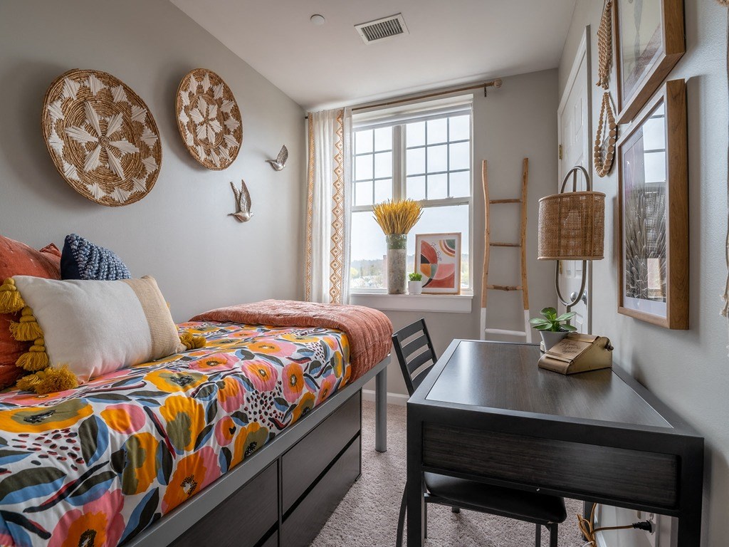 a bedroom with a bed and a desk and a window
