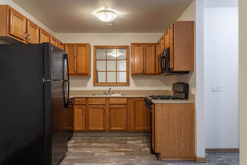 A kitchen with wooden cabinets and a black refrigerator.