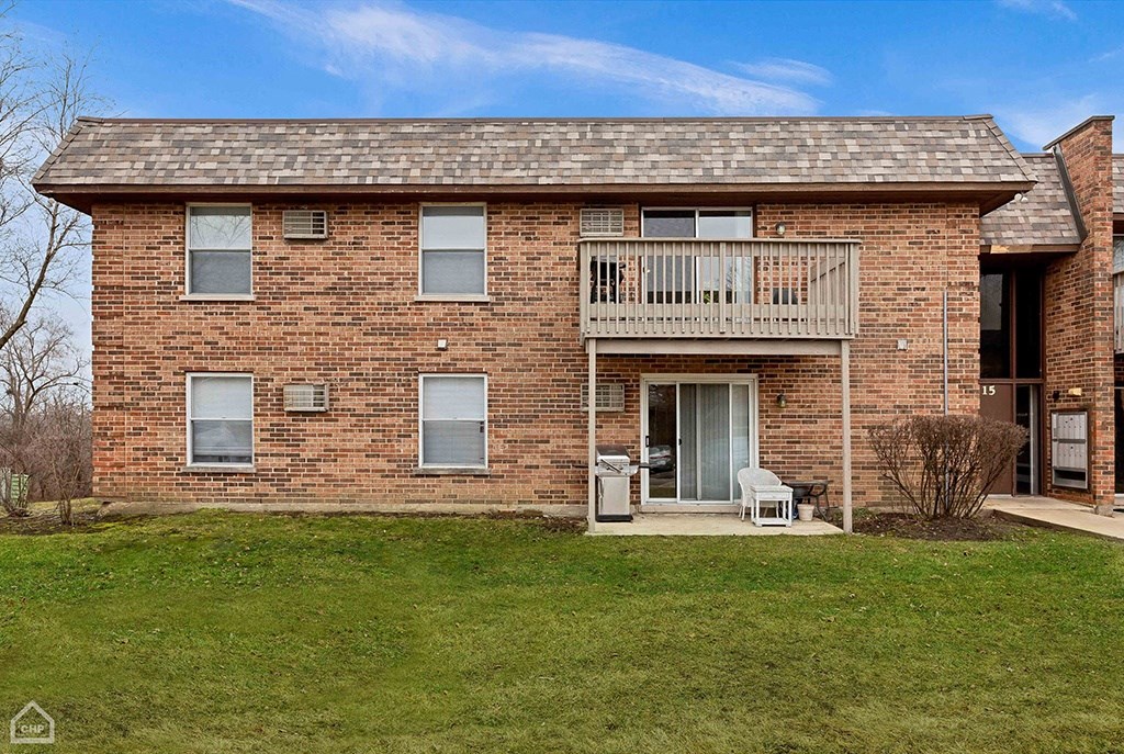 a brick house with a balcony and a green yard