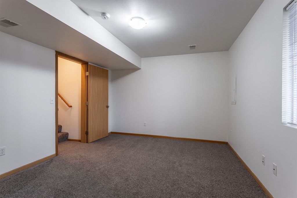 A room with a carpeted floor and a wooden door.