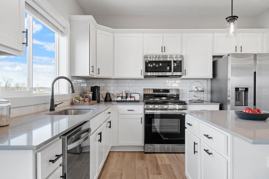 a large white kitchen with stainless steel appliances and white cabinets