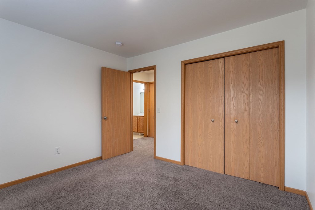 A room with a carpeted floor and two wooden doors.