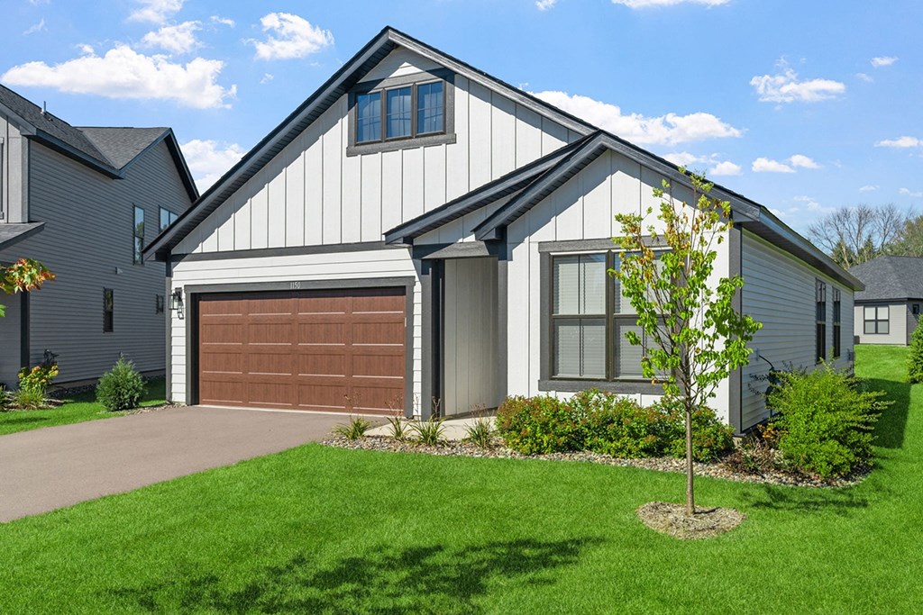 a home with a brown garage door in front of a green lawn