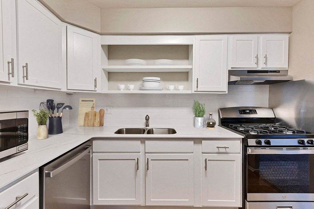 a white kitchen with stainless steel appliances and white cabinets