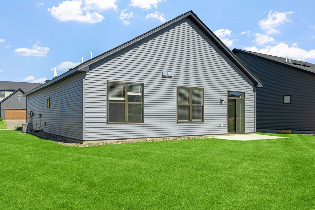 a gray house with a green lawn in front of it